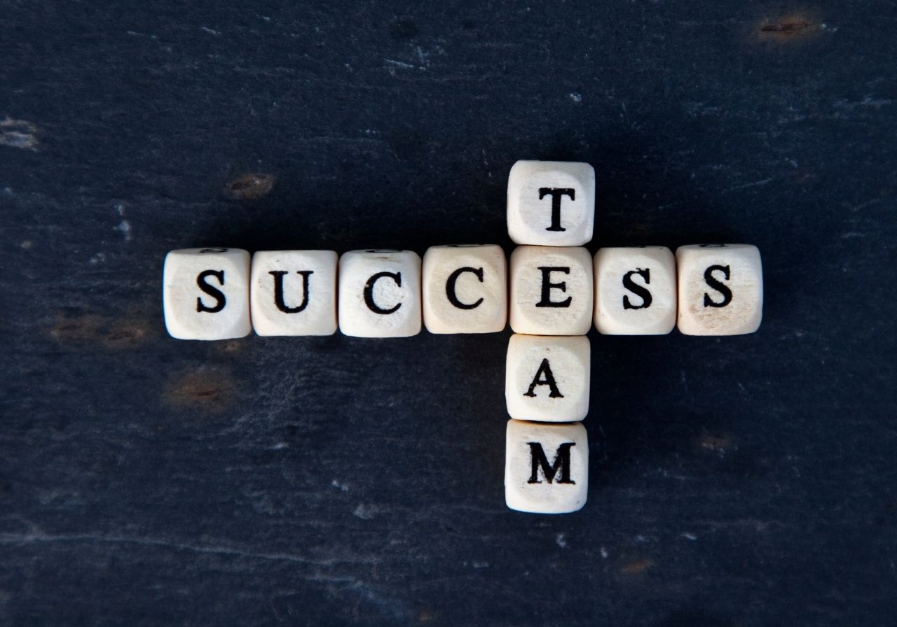 Wooden letter blocks arranged to spell 'SUCCESS' and 'TEAM' on a dark surface.